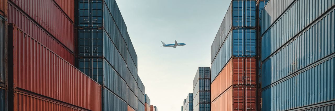 Aereo che vola in cielo aperto circondato da container colorati 