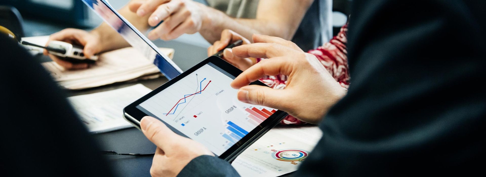 Un manager controlla dei dati sul tablet e altri colleghi si confrontano