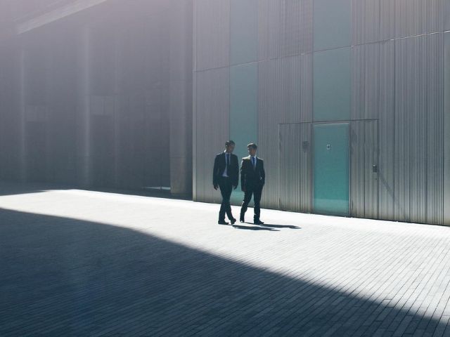 Due colleghi esperti di rischio finanziario si confrontano nel cortile esterno dell'azienda