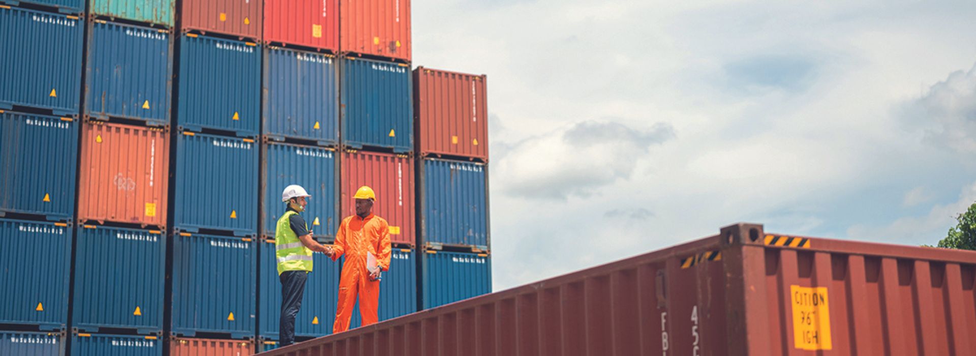 Un ingegnere e un operaio si stringono la mano in un deposito container