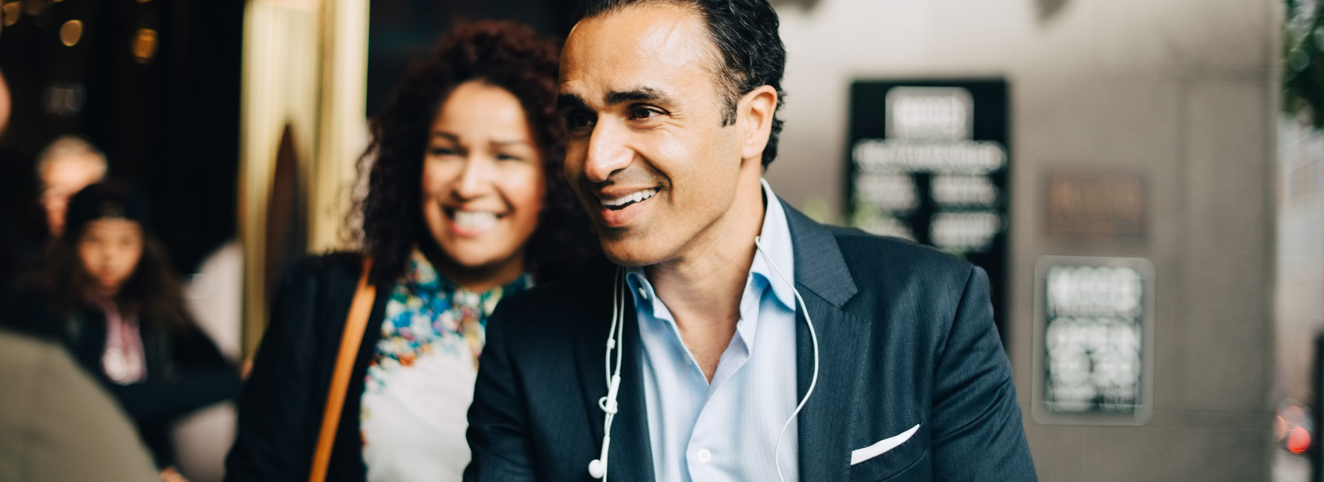 Un uomo e una donna sorridenti salutano un collega