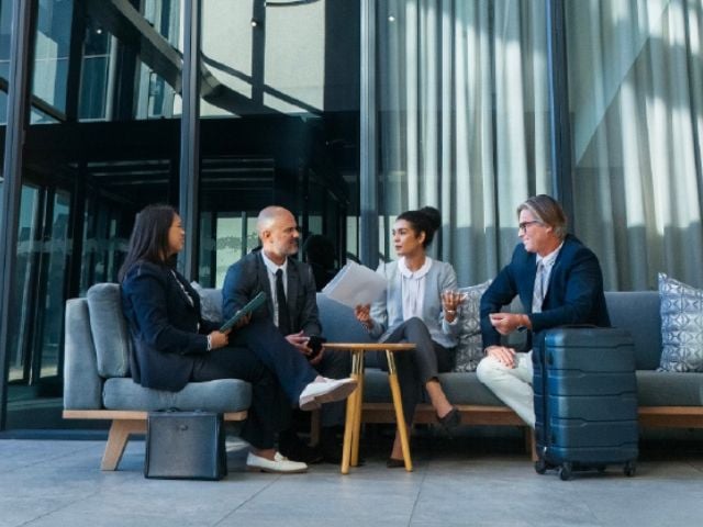 Quattro persone con abiti da lavoro conversano su un divano