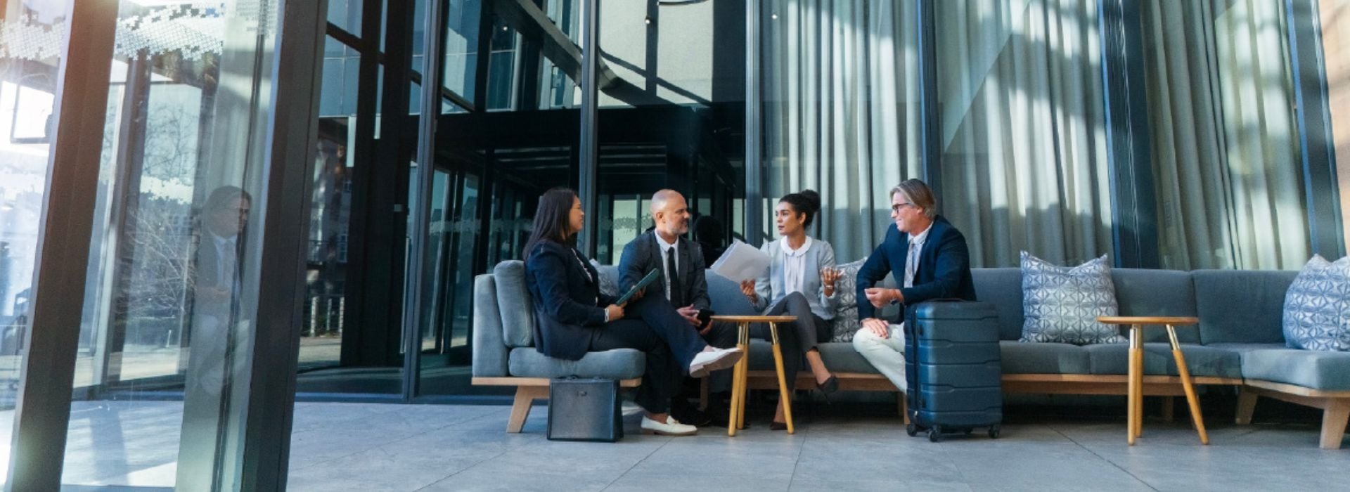 Quattro persone con abiti da lavoro conversano su un divano