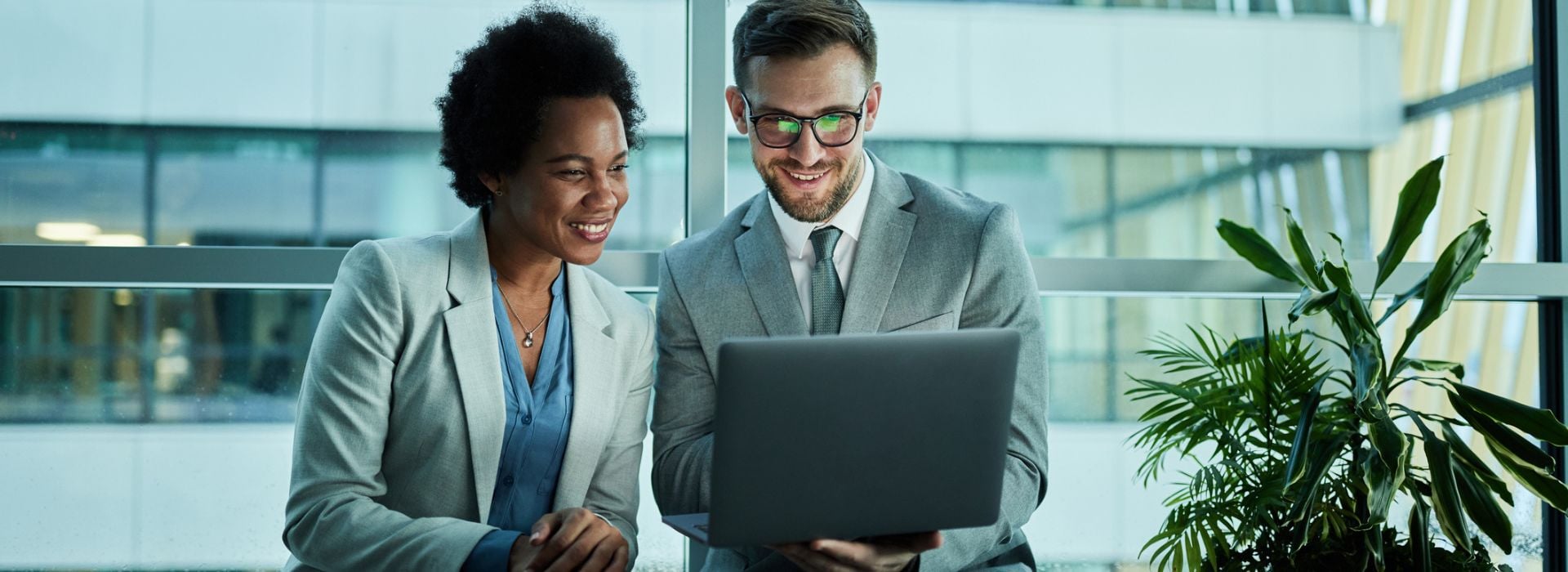 Due persone che guardano lo schemo del computer e sorridono