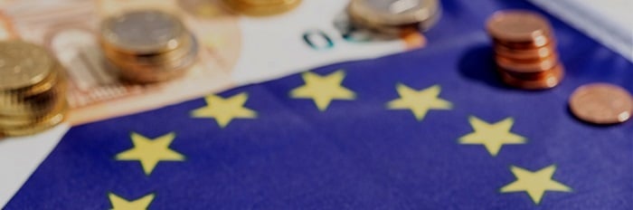 Monete e banconote in euro sopra la bandiera dell'Unione Europea