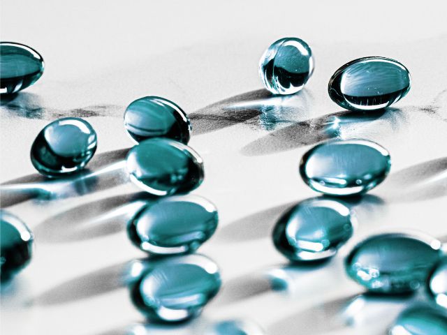 Capsule medicinali di colore celeste, disposte su una superficie piana