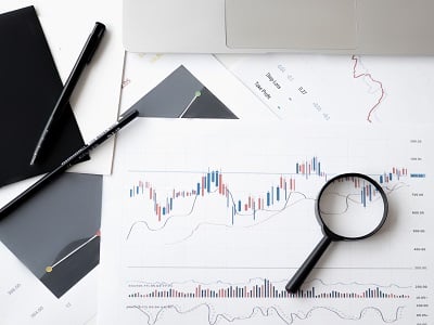 Penne, lente d'ingrandimento e documenti con grafici su una scrivania