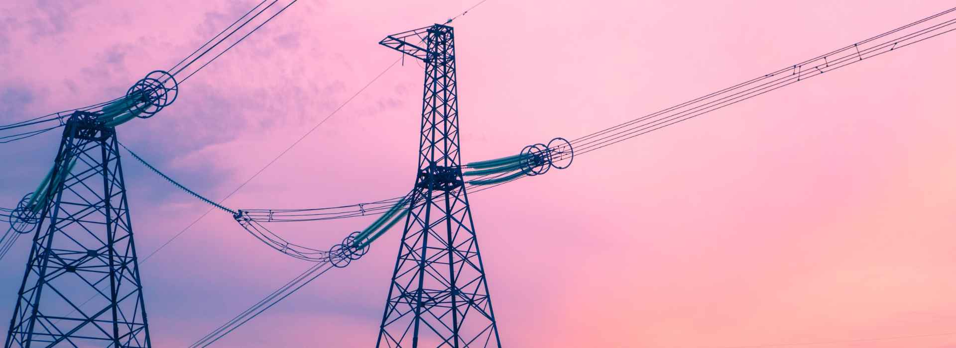 Tralicci elettrici con cielo rosa sullo sfondo