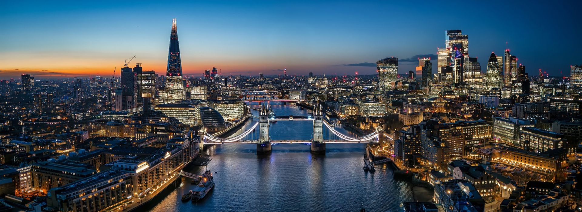 Tower Bridge di Londra all'alba, illuminato e riflesso sulle acque del Tamigi. 