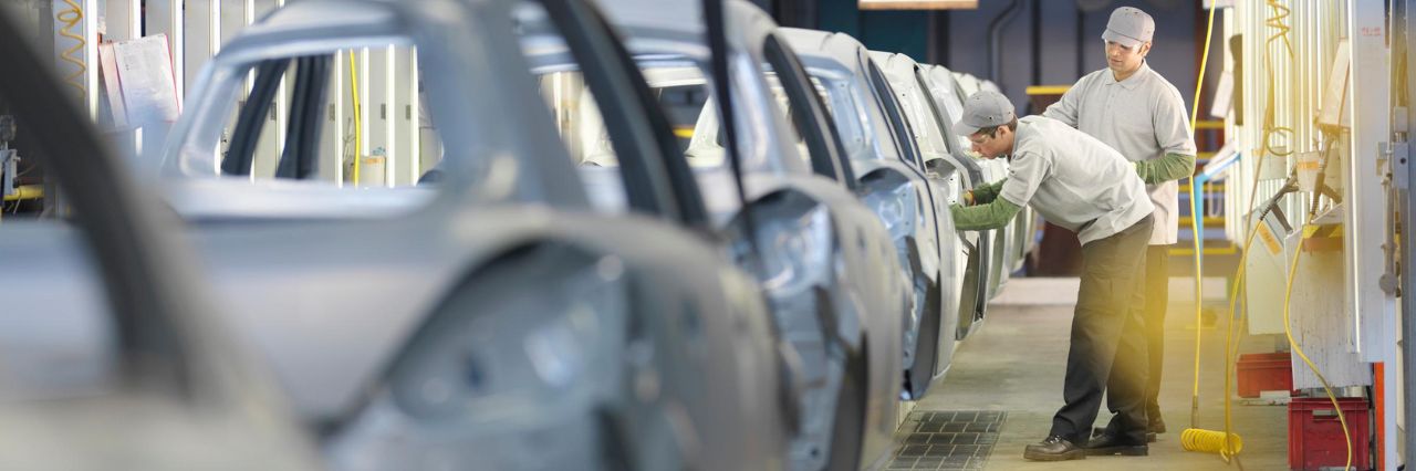 Due operai lavorano in un'industria automobilistica