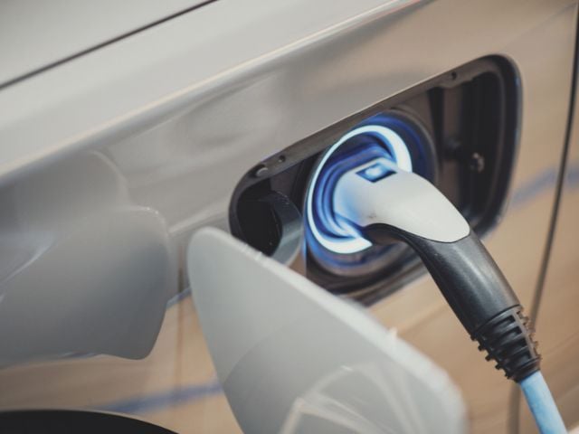 Auto elettrica mentre si ricarica tramite cavo collegato alla presa.