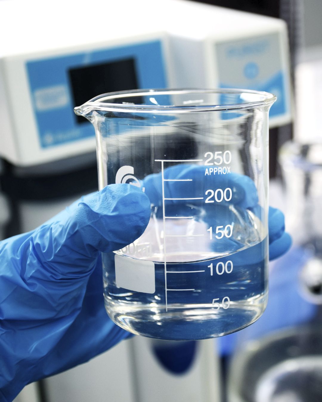 In un laboratorio, un chimico lavora con un becher contenente una sostanza liquida trasparente
