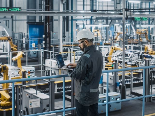 Immagine di una persona con un elmetto che sta lavorando al computer 