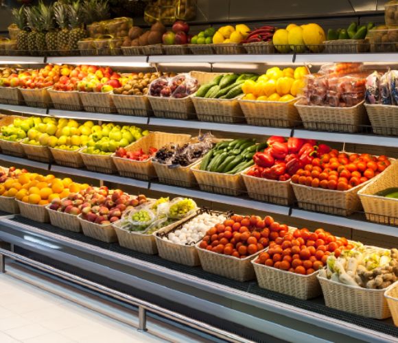 Reparto ortofrutta all'interno di un supermercato, con espositori ricchi di frutta e verdura fresca e colorata