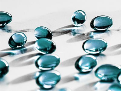 Capsule medicinali di colore celeste, disposte su una superficie piana