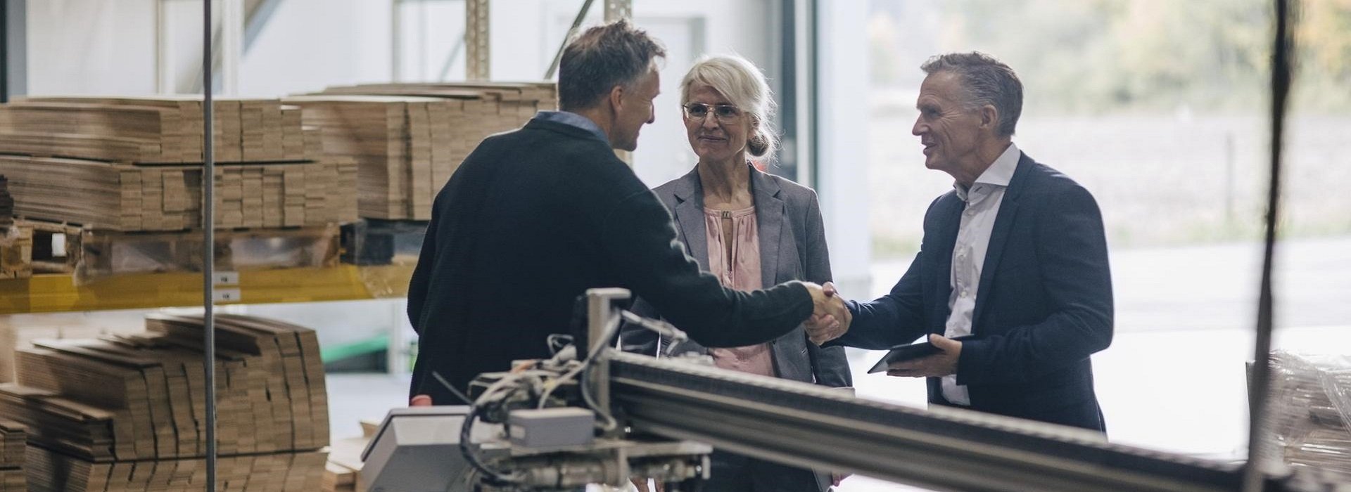 Un imprenditore si presenta a due clienti nel laboratorio della sua azienda