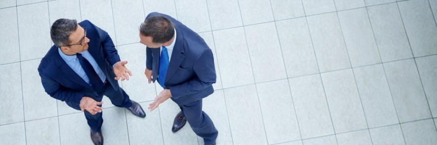 Twee mannen in pak die praten over de impact van tariefverschuivingen op hun business