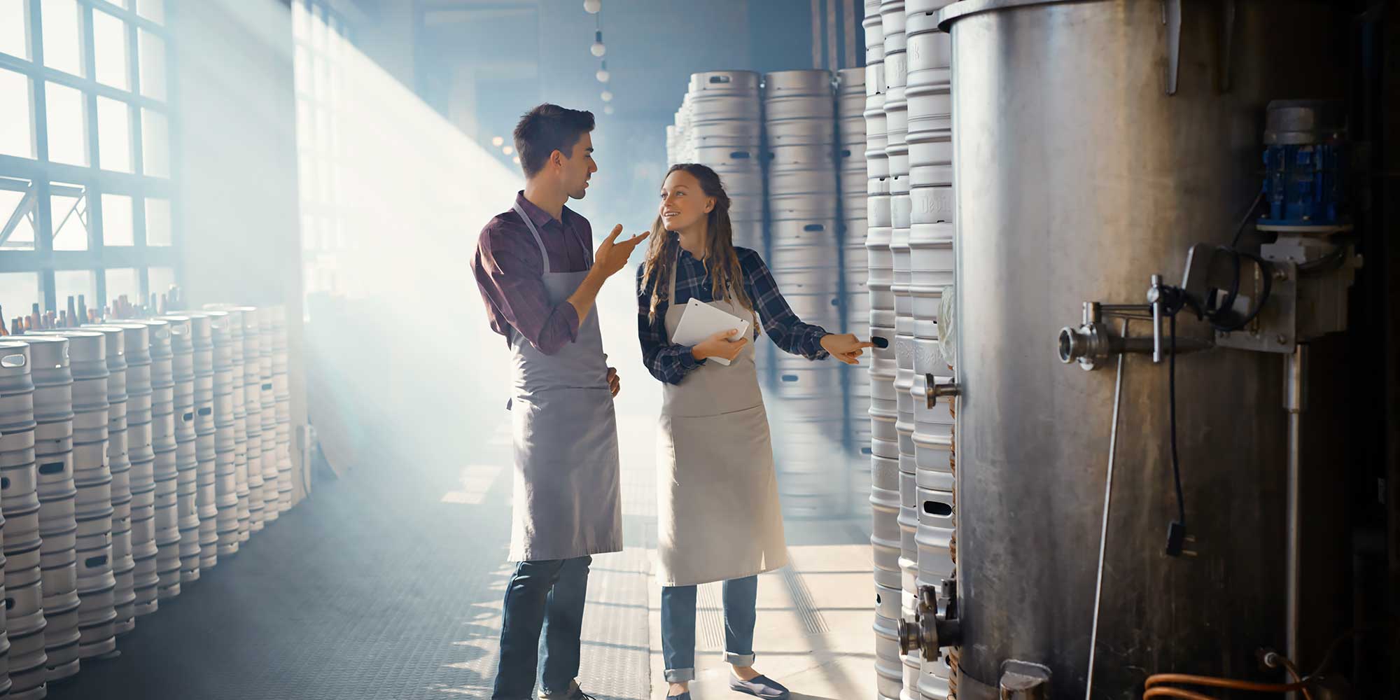 Kobieta z mężczyzną rozmawiają w magazynie z beczkami