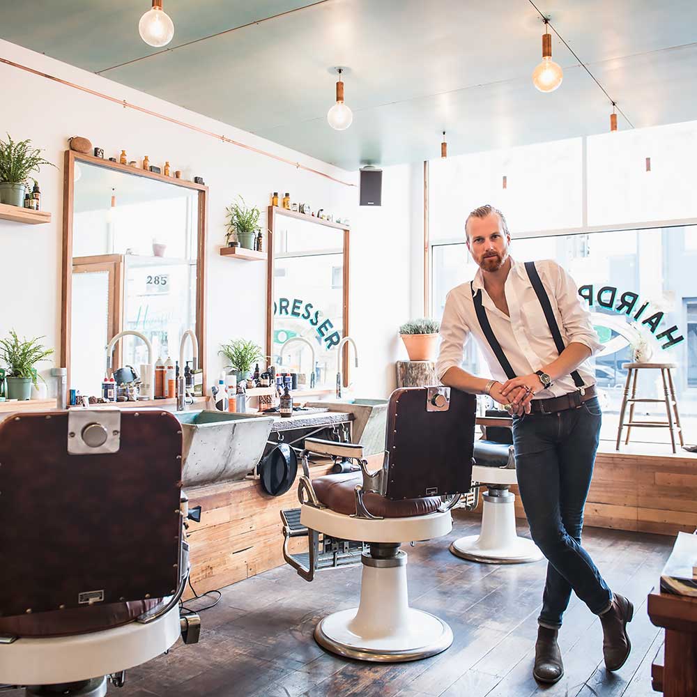 Fryzjer w salonie opiera się o fotel fryzjerski