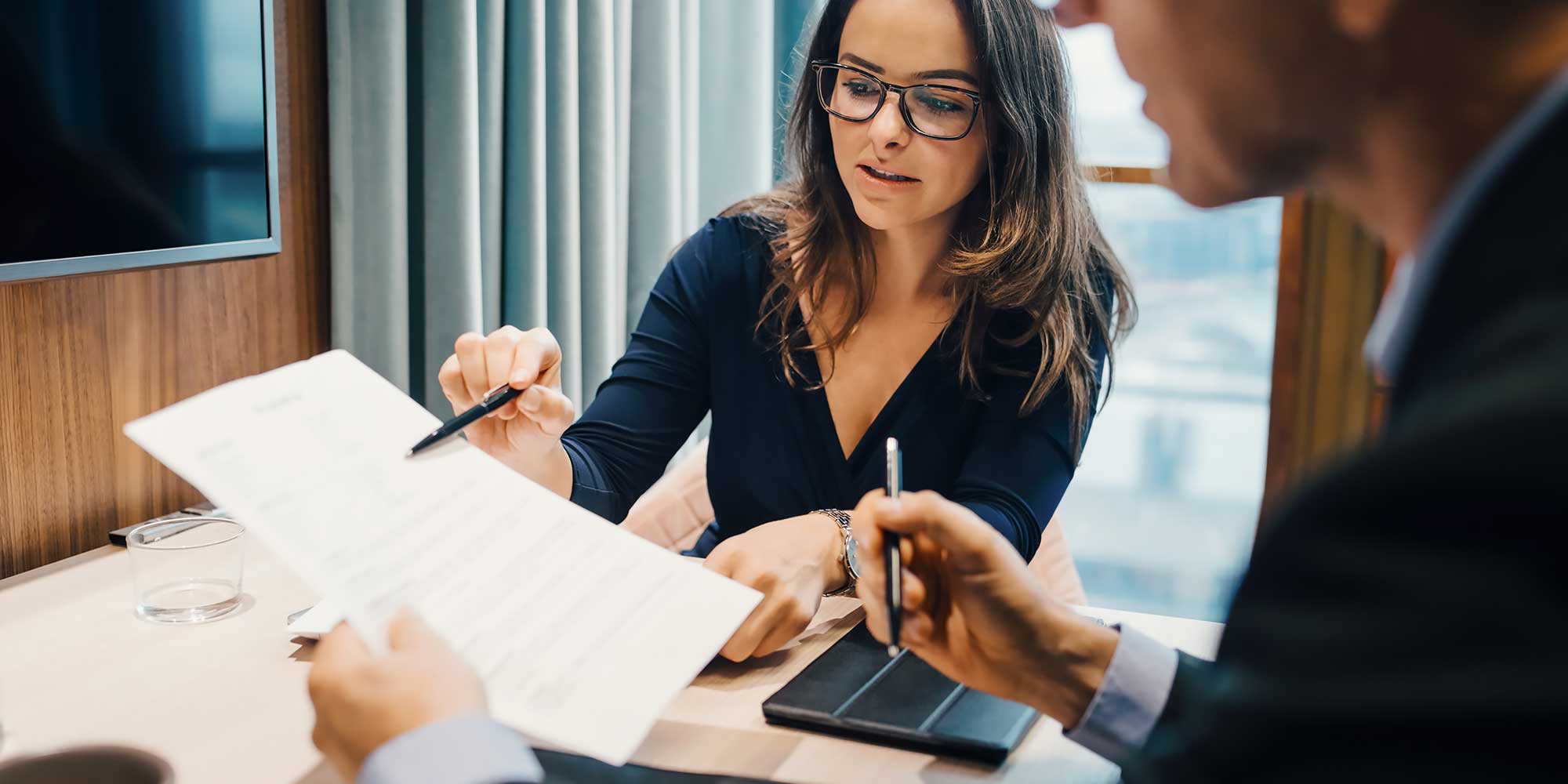 Kobieta z długopisem wręku wskazuje na kartkę papieru