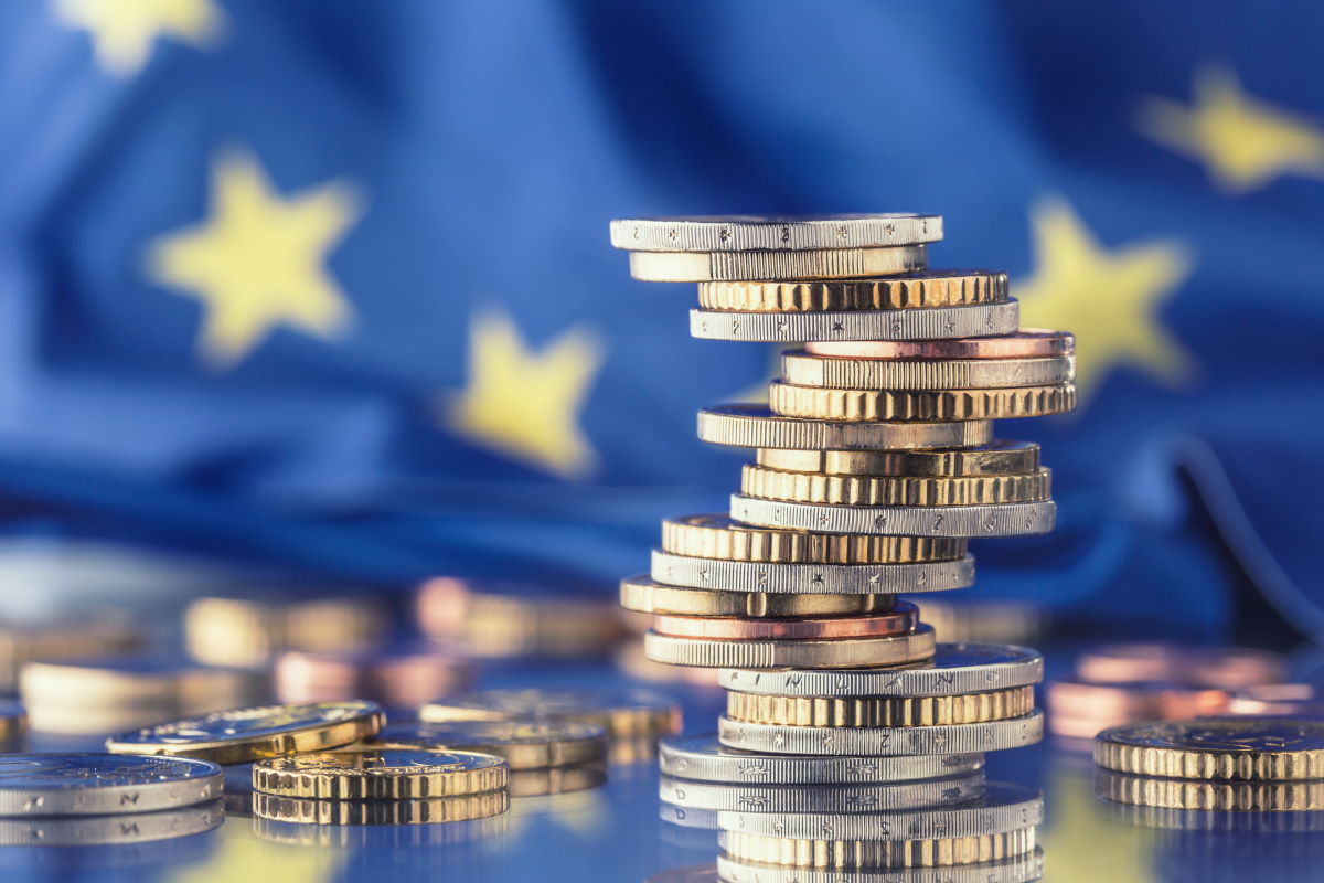 Europejskie monety ułożone na niebieskiej powierzchni z flagą