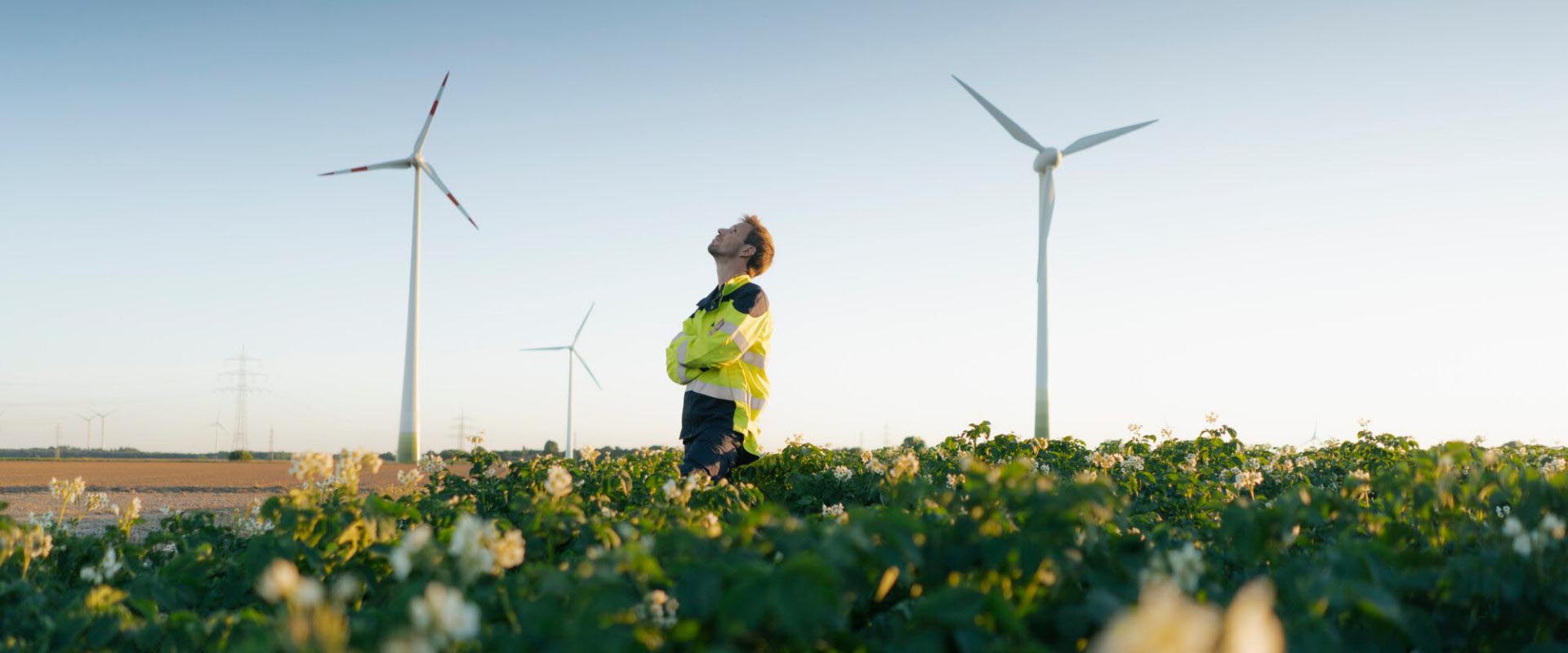 Mężczyzna stojący przy wiatraku na polu kwiatów
