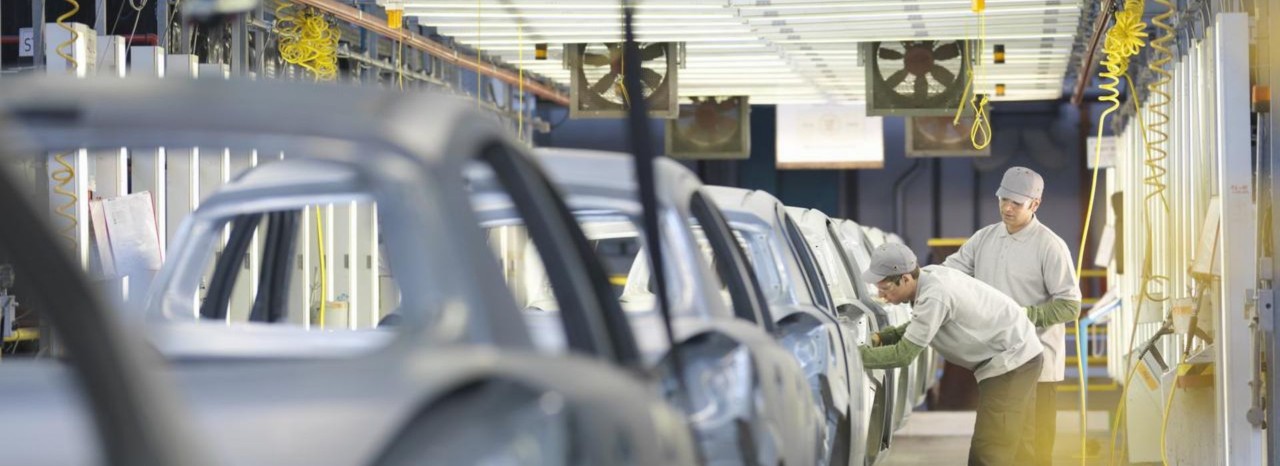 Mężczyźni pracujący nad ramami samochodów w fabryce