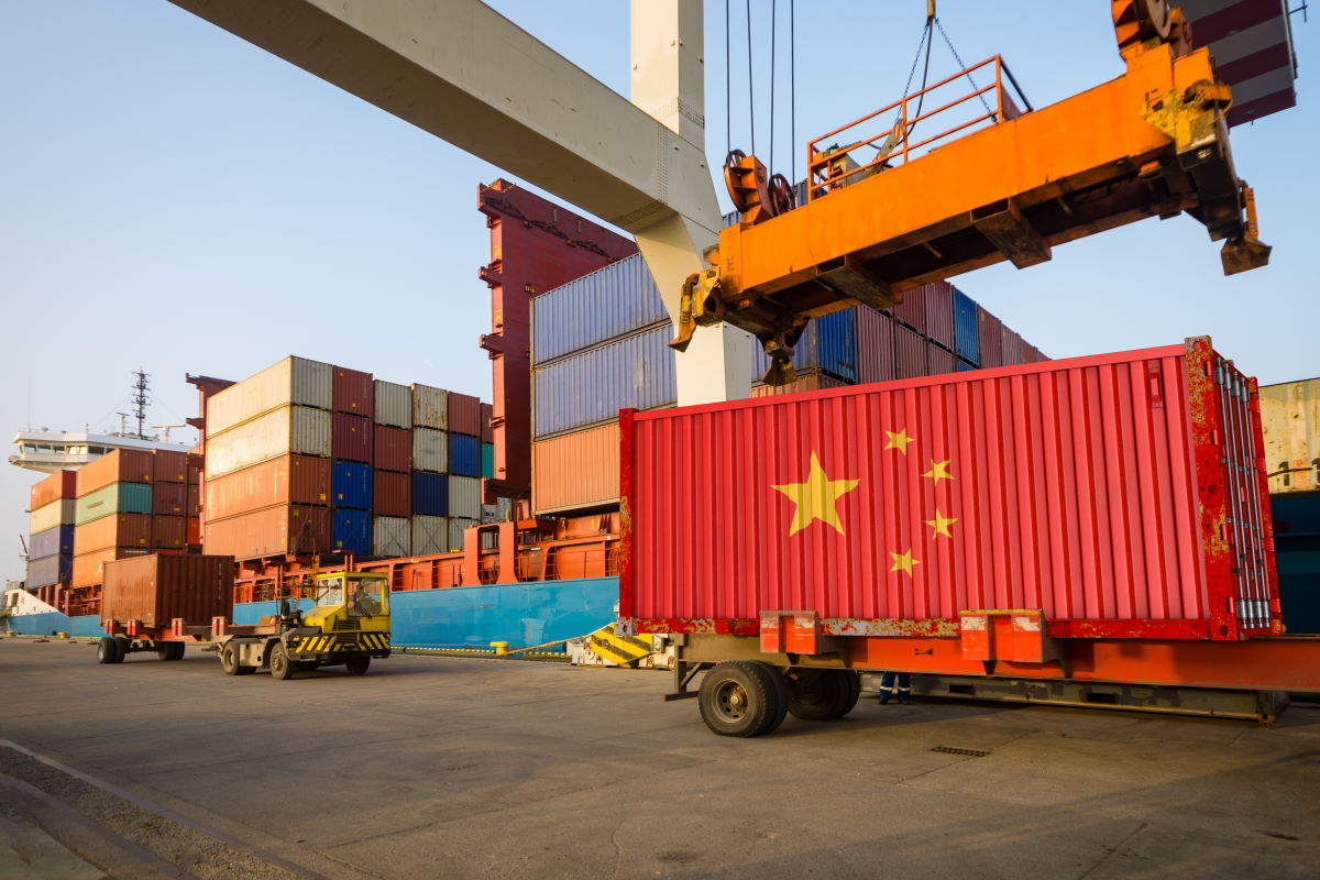 Dźwig towarowy podnoszący kontener transportowy z chińską flagą