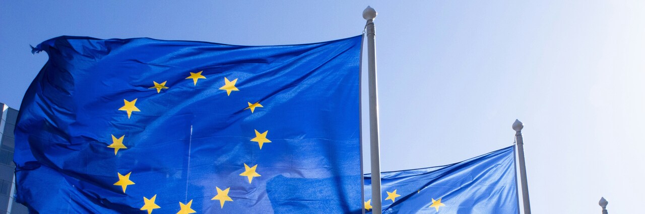 Flaga Unii Europejskiej powiewająca na błękitnym niebie