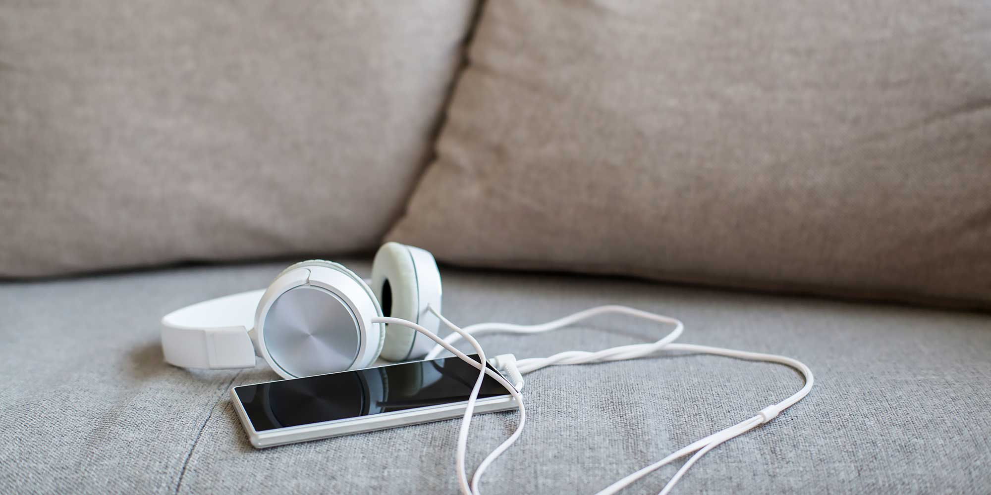 Telefon z podpiętymi słuchawkami na kanapie