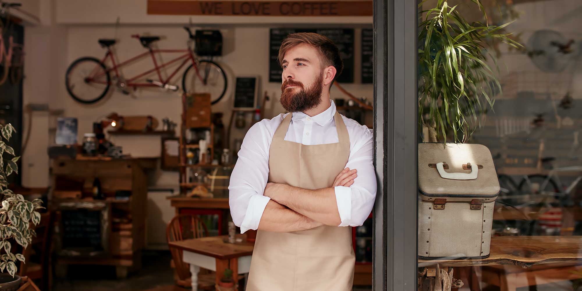 Mężczyzna stojący przed sklepem z założonymi rękoma