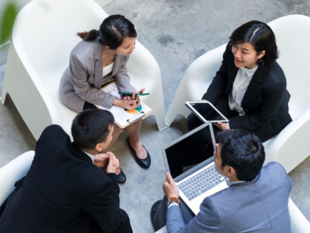 Pessoas de negócios sentadas com portatil a falar sobre o Seguro de Crédito