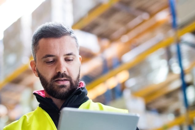 Man in warehouse looking at a ipad like he is checking something
